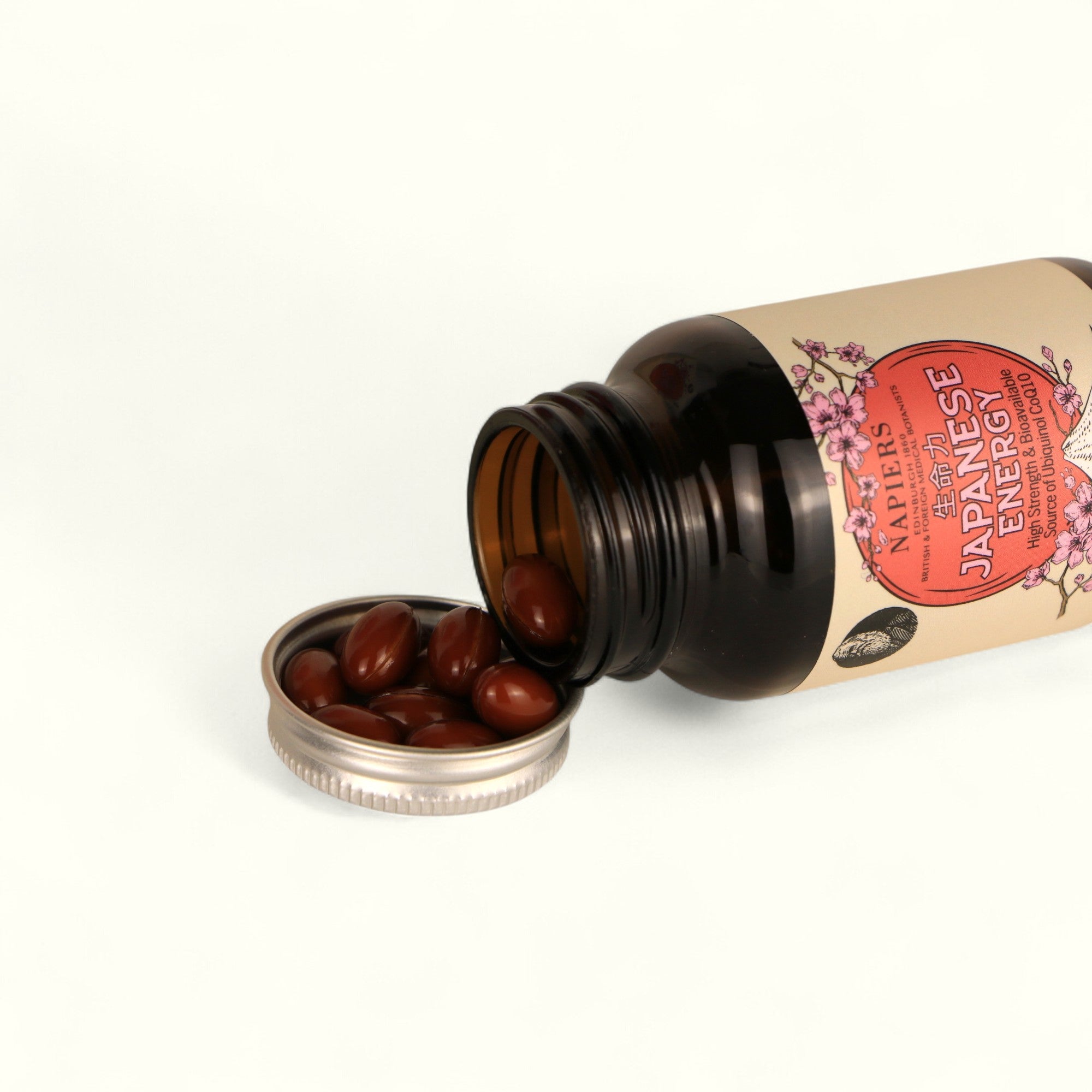 Napiers Japanese Energy CoQ10 capsules spilling from bottle showing reddish-brown ubiquinol form