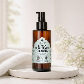 Napiers Rowan Brightening Cleanser on ceramic dish with white towel and white flowers in styling