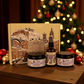 Napiers Mum & Baby Gift Box with cream, balm, and sleep spray displayed against Edinburgh illustration packaging, surrounded by festive decorations.